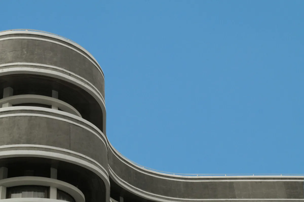 A concrete building with a curved balcony sweeping out against a plain blue sky